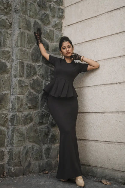Raven Black Co-ord Set, MidWeek Women's Formal Wear - Workwear Style India, Woman in a black peplum dress standing against a stone wall.