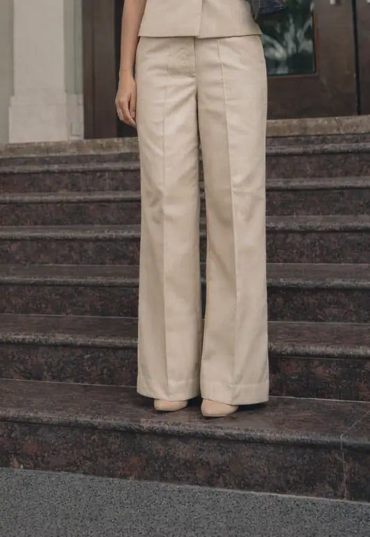 Person wearing a beige suit standing on stone steps.