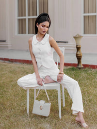 Woman in a white outfit sitting on a chair outdoors