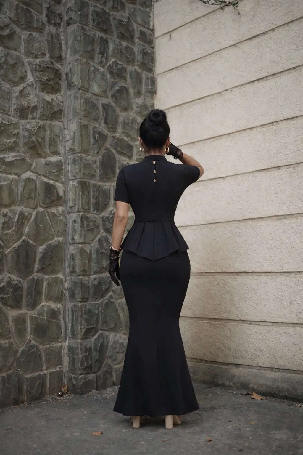 , MidWeek Women's Formal Wear - Workwear Style India, Woman in a black dress standing against a stone wall.