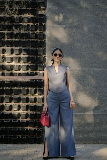 Woman in a stylish outfit standing against a textured wall.