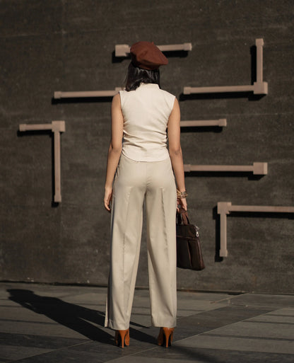 Woman in beige outfit and brown beret walking away from a dark wall with geometric shapes.