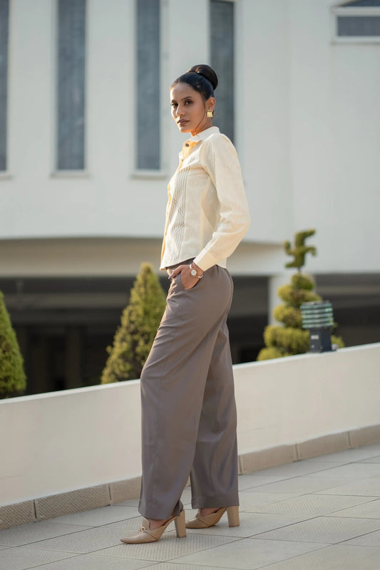 Woman in a white blouse and gray pants standing on a rooftop with a blurred building background