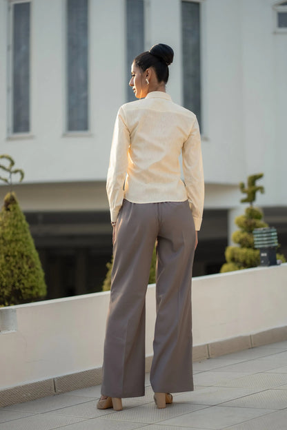 , MidWeek Women's Formal Wear - Workwear Style India, Woman in a light-colored blouse and gray pants standing on a rooftop with a building in the background.