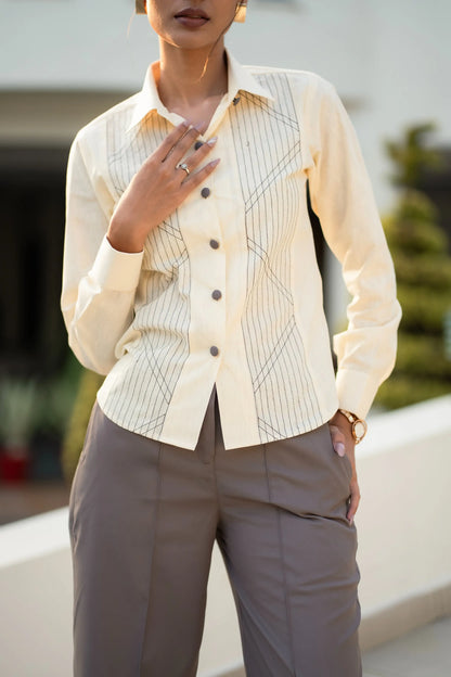 , MidWeek Women's Formal Wear - Workwear Style India, Person wearing a cream-colored button-up shirt with a geometric pattern and brown pants outdoors.