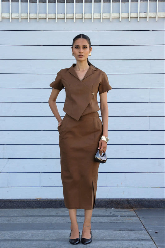 Woman wearing a brown outfit against a light blue wall.