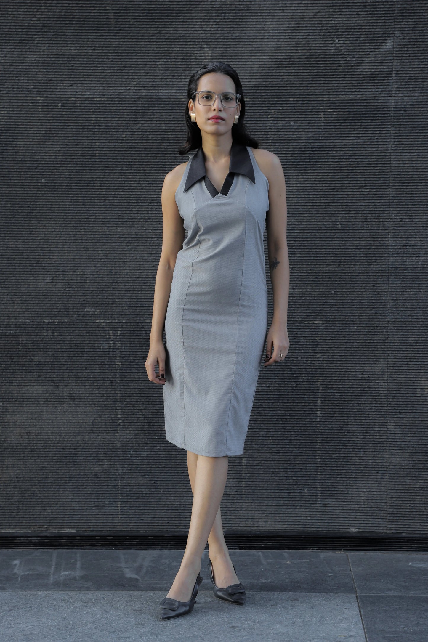 , MidWeek Women's Formal Wear - Workwear Style India, Woman wearing a gray dress with a black collar against a dark textured wall.