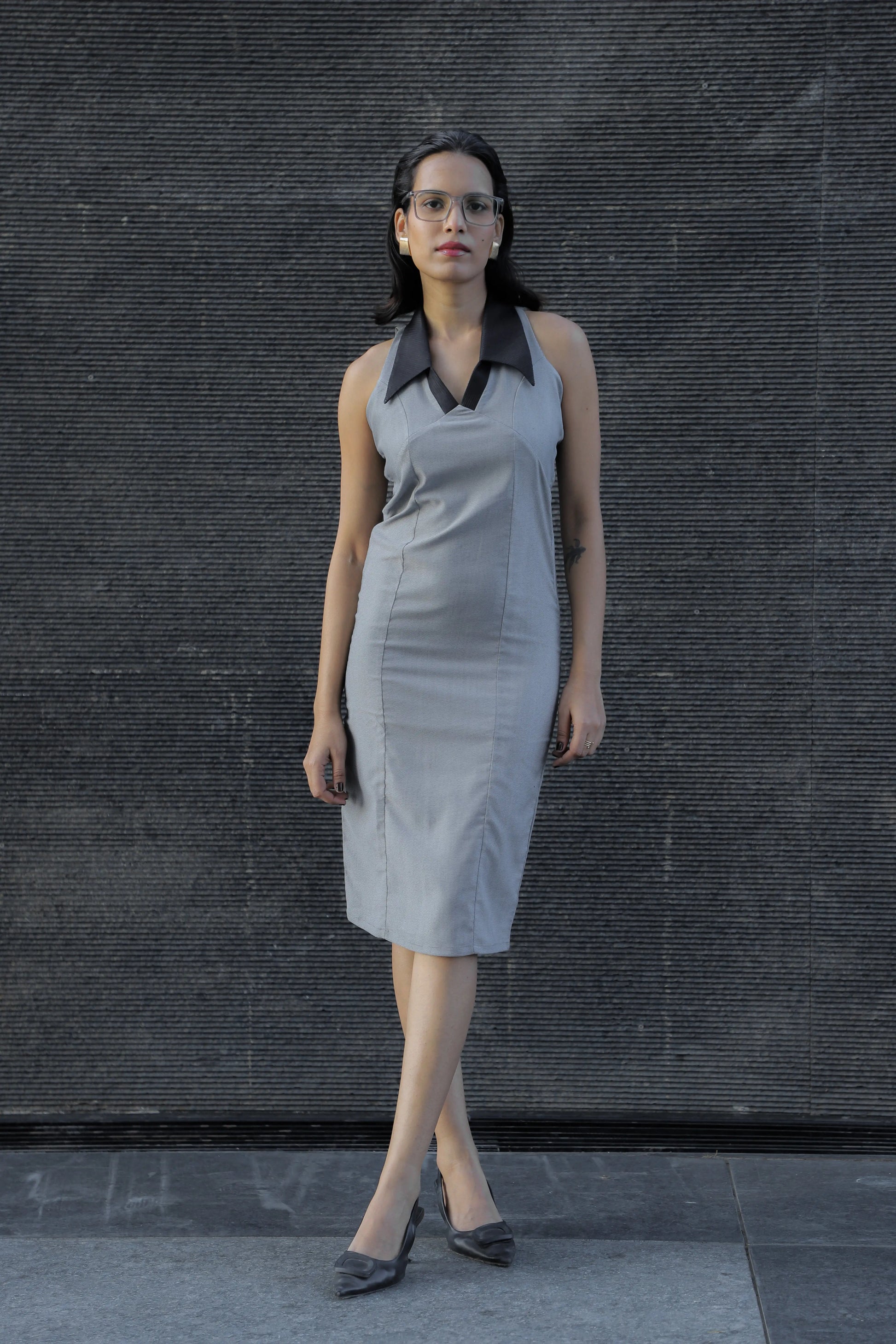 , MidWeek Women's Formal Wear - Workwear Style India, Woman wearing a gray dress with a black collar against a dark textured wall.