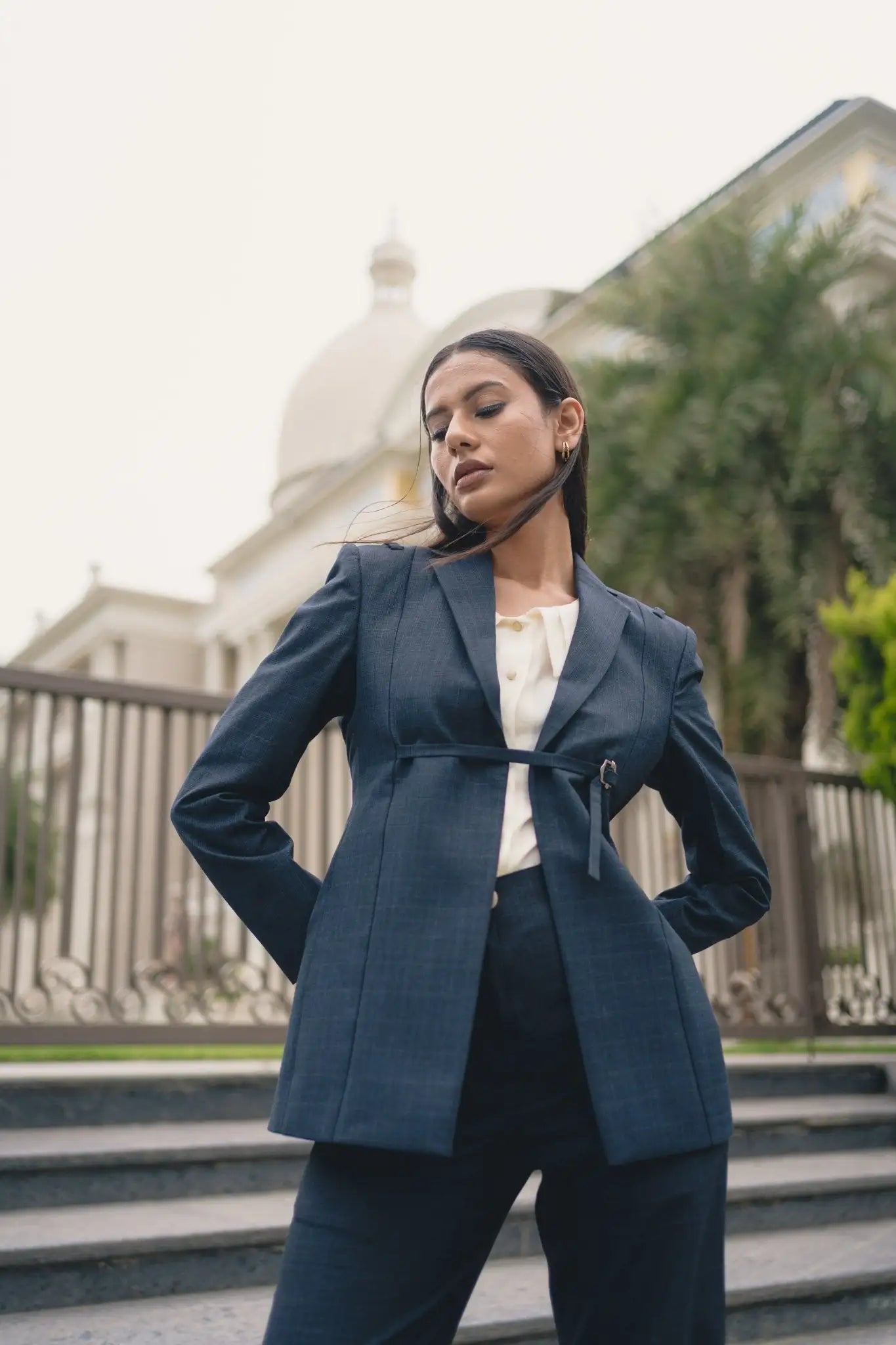 Woman in a blue suit standing outdoors with a blurred background